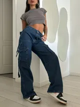 Pantalón de jean azul oscuro, de tiro bajo y corte ancho, con bolsillos cargo laterales y lazos ajustables.