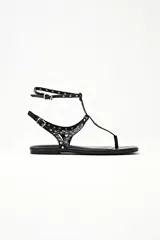 Sandalias negras tipo ojotas con tiras finas y tachas plateadas.