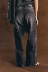 Jean de denim tiro alto con diseño baggy de corte ancho y relajado, color negro con efecto acid wash. Presenta cierre frontal con botón metálico y bolsillos clásicos.
