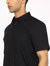 Camisa negra de manga corta con corte slim fit, cuello clásico y cierre con botones.