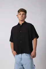 Camisa de manga corta confeccionada en una mezcla de lino y viscosa, de color negro. Presenta un calce regular, cuello plano y cierre frontal con botones a contraste. Su tejido liviano y respirable ofrece una textura natural ideal para climas cálidos.