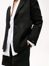 Blazer negro de lino con corte regular, solapas con muescas, botonadura sencilla, bolsillo de parche en el pecho y dos bolsillos delanteros de parche. Forro de algodón.