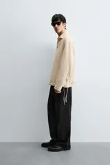 Pantalón de corte regular fit confeccionado en mezcla de algodón y lino. Presenta cintura elástica con cordón ajustable, cierre frontal con cremallera y botón, bolsillos laterales y bolsillo trasero de vivo con botón.