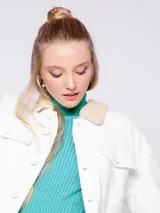 Campera de jean azul con interior forrado en corderito color crema. Presenta cuello camisero, cierre frontal con botones metálicos y dos bolsillos frontales con solapa.