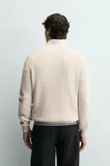 Jersey de punto perlado con cuello perkins y cierre frontal de cremallera. Presenta un corte regular fit, manga larga y acabados en rib en puños y bajo.