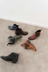 Botín negro de cuero con elásticos laterales, taco bajo y tirador trasero.