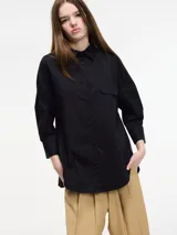 Camisa negra de algodón con botones frontales, cuello camisero y bolsillo con solapa en el pecho.