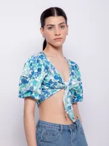 Top estampado con flores rosas, hojas verdes y líneas negras, de manga corta abullonada con nudo en el escote.