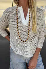 Buzo de tejido de punto calado color beige claro, con cuello tipo polo en color blanco. Manga larga.