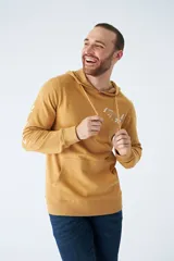 Buzo canguro color mostaza con capucha ajustable mediante cordones, bolsillo frontal tipo canguro y estampado gráfico en el pecho. Presenta puños y ruedo acanalados.