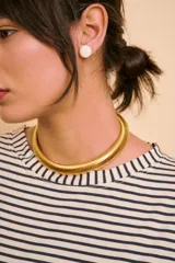 Gargantilla rígida de metal dorado, diseño tubular y texturizado con acabado brillante.