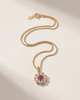 Collar de bronce con cadena fina dorada y dije en forma de flor con circonias brillantes y una piedra central de color rojo.