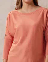 Buzo tejido color salmón de hilado fino, marca Cable & Gauge. Escote redondo con calados. Manga ¾, modelo dolman con aplique de botones dorados.