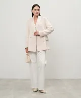 Blazer cruzado de lana color crudo, con solapas, cierre con botones a tono, manga larga con aberturas y bolsillos con solapa.