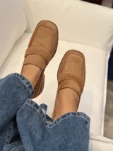 Mocasín de punta cuadrada confeccionado en piel con textura de pelo, color beige tostado, con detalle de antifaz en el empeine y costuras visibles en el borde.