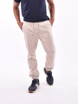 Pantalón tipo jogger de gabardina color beige, con cintura elástica ajustable mediante cordón, bolsillos laterales y puños elásticos en los tobillos.