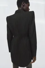 Blazer vestido de Zara con diseño de raya diplomática, cuello solapa con muesca, hombreras marcadas y cierre frontal cruzado con botones. Presenta una cintura entallada con volumen y falso bolsillo de vivo en el pecho.