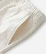 Bermuda recta de playa en color blanco roto, confeccionada en algodón texturizado con efecto de rayas verticales. Posee cintura elástica con cordón ajustable.