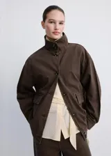 Chaqueta de algodón estilo tejano vaquero, color marrón, de diseño oversize con cuello alto, manga larga, bolsillos delanteros de parche y solapa, y cierre frontal con botones.