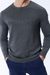 Buzo de punto en color gris oscuro, con cuello redondo y mangas largas. Presenta puños y ruedo acanalados para un ajuste cómodo.