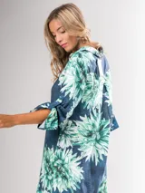 Vestido camisero largo con estampado floral en tonos rojos y negros, con cuello camisero, abotonadura frontal y mangas largas con puños abotonados.