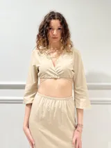 Top color beige, con escote en V, mangas 3/4 y abertura en el abdomen.