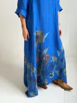 Vestido largo azul con cuello en V, mangas tres cuartos y gran estampado floral en la parte inferior.