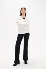 Sweater de punto color blanco, con cuello en V, manga larga y diseño holgado.
