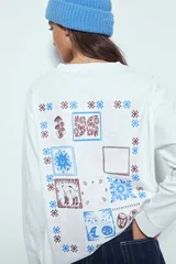 Remera de manga larga negra con cuello redondo y puños blancos visibles, presentando un estampado gráfico con motivos celestiales en el pecho.