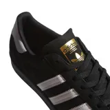 Championes adidas Superstar ADV, modelo clásico con puntera de goma, confeccionados en gamuza negra con las icónicas tres tiras laterales en blanco y detalle de logo dorado en la lengüeta.