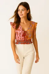 Top sin mangas de viscosa con estampado paisley en tonos naranja y rosa, con volados en los hombros, corte al cuerpo, escote en V profundo y lazo ajustable en el frente.