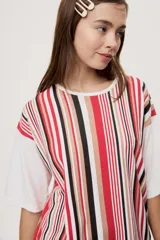 Remera oversize de manga corta con diseño de rayas verticales en tonos rojos, negros, blancos y tostados, y mangas blancas lisas.