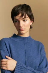 Polera de tejido de punto color blanco, con cuello alto acanalado, hombros caídos y detalle de costura vertical en el frente.