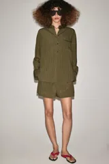 Camisa fluida de mujer de la ZW Collection de Zara, confeccionada en mezcla de viscosa, con diseño a rayas en tonos verde militar y marrón oscuro. Presenta cuello solapa, manga larga con puños anchos terminados en ribete negro a contraste, bolsillo de parche en el pecho con ribete a juego, bajo redondeado y cierre frontal con botones oscuros.
