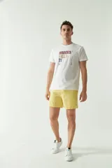 Short de baño liso con cintura elástica y cordón de ajuste. Cuenta con dos bolsillos laterales, un bolsillo trasero y logo bordado en el ruedo. Confeccionado en tela ligera de secado rápido.