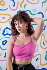 Top corto de algodón elastizado en color rosa, con breteles finos y un pequeño aplique decorativo circular en el centro del pecho.