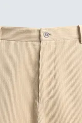 Pantalón de corte regular fit confeccionado en pana de algodón color beige, con bolsillos frontales, bolsillos traseros de plastrón y cierre frontal con cremallera y botón.