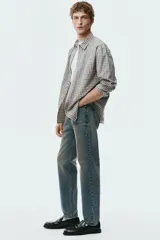 Jean de corte recto en denim de algodón rígido, con diseño de cinco bolsillos y acabado con efecto desgastado.