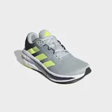 Championes de running Adidas Questar 3, color gris claro con tres franjas laterales en amarillo neón. Presentan detalles en azul oscuro en el talón y la suela, con entresuela blanca y tecnología Cloudfoam Plus.