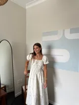 Vestido midi blanco con estampado floral celeste, escote cuadrado con detalle de lazo, mangas cortas abullonadas y falda con volados.