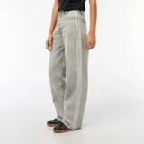 Jean de corte baggy en color gris con efecto lavado ácido. Presenta bandas laterales en tono plateado brillante y diseño de cinco bolsillos con cierre de botón y cremallera.