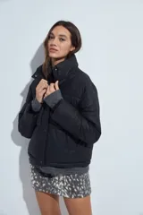 Campera puffer de nylon color marrón oscuro, con cuello alto, cierre frontal y puños elásticos. Diseño acolchado de volumen ligero.