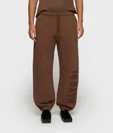 Pantalón deportivo oversize de felpa, color marrón, con cintura elástica y cordón ajustable. Presenta puños acanalados y un parche bordado con el texto "10 DAYS" en el lateral de la pierna.
