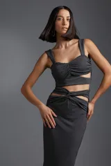 Top negro con estampado de lunares blancos, breteles anchos y detalle de flor blanca en el centro.