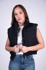 Chaleco puffer corto negro con cuello elevado, cierre frontal y diseño acolchado.