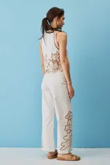 Pantalón negro de tiro alto y corte recto, confeccionado con detalles de bordados florales calados en la parte inferior de las piernas.