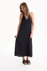 Vestido largo negro de corte holgado, con escote en V y tirantes finos tipo halter.