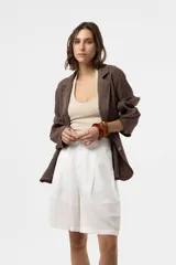 Chaqueta de lino verde militar de calce relajado, con solapa clásica, cierre frontal con dos botones grandes y bolsillos delanteros con solapa.
