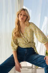 Blusa cruzada con estampado floral en tonos amarillo y blanco. El cruce se ajusta a la cintura con un lazo. Tiene mangas 3/4.