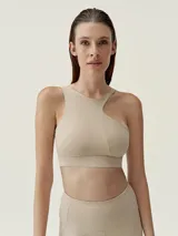 Top deportivo color beige con diseño asimétrico y tirante ancho en un hombro.